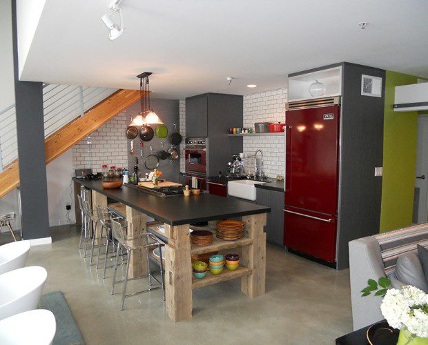 A kitchen with a red refrigerator and black counter.